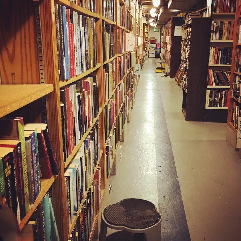 an aisle of book shelves that have mystery-genre fiction on them